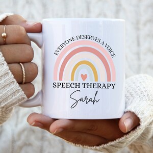Puede incluir: Taza de cerámica blanca con un diseño de arcoíris y el texto "Todos merecen una voz" y "Logopedia Sarah".