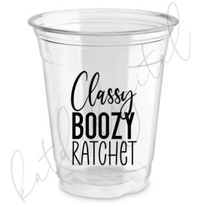 Peut inclure: Gobelet en plastique transparent avec du texte noir qui dit "Classy Boozy Ratchet".