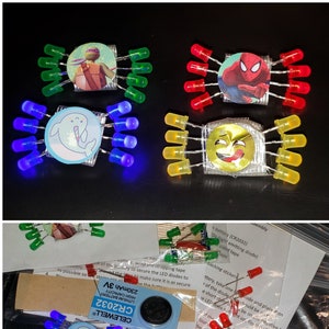 May include: Four LED light-up crafts with different characters. The crafts are made with LED lights, batteries, and cardboard. The characters are a Teenage Mutant Ninja Turtle, Spiderman, a narwhal, and a smiley face.