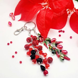 May include: A silver key chain with red, green and black beaded charms. The charms are shaped like peppers and have a shiny finish.