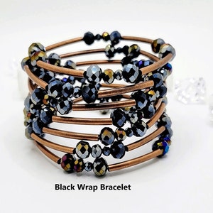 May include: A multi-strand bracelet made of copper wire and black iridescent beads. The bracelet is wrapped around itself to create a spiral effect. The beads are small and round, and they have a subtle sparkle.
