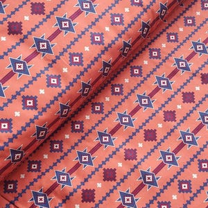 May include: A fabric featuring a repeating geometric pattern on a coral orange background. The design includes horizontal bands of dark purple stripes, blue diamond shapes with white outlines, and small purple and white cross-like motifs.