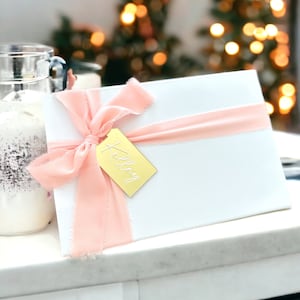 May include: A white gift box with a pink ribbon and a gold gift tag that says "Kelley".
