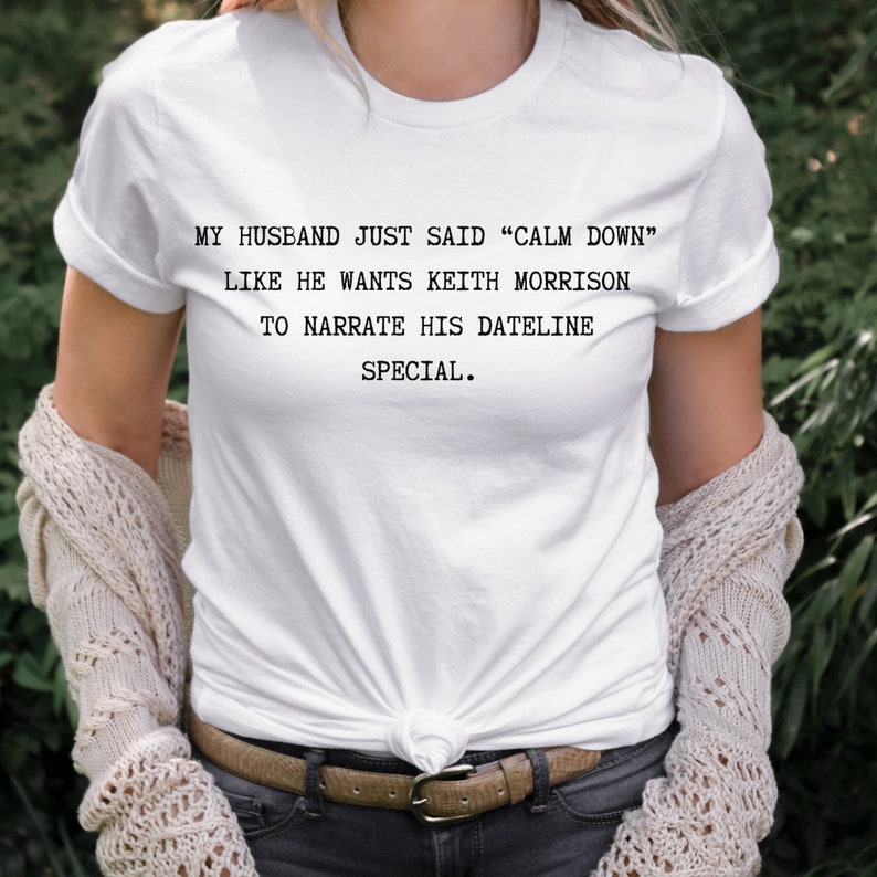 May include: White t-shirt with the text "MY HUSBAND JUST SAID "CALM DOWN" LIKE HE WANTS KEITH MORRISON TO NARRATE HIS DATELINE SPECIAL."