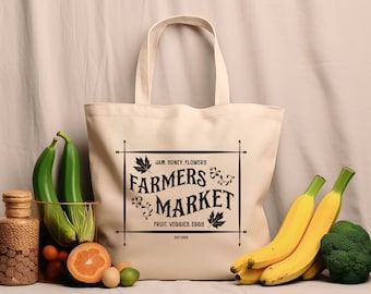 May include: A white canvas tote bag with black text that reads "JAM, HONEY, FLOWERS, FARMERS MARKET, FRUIT, VEGGIES, EGGS, EST 1980". The bag is sitting on a table with a variety of fruits and vegetables, including bananas, zucchini, and broccoli.