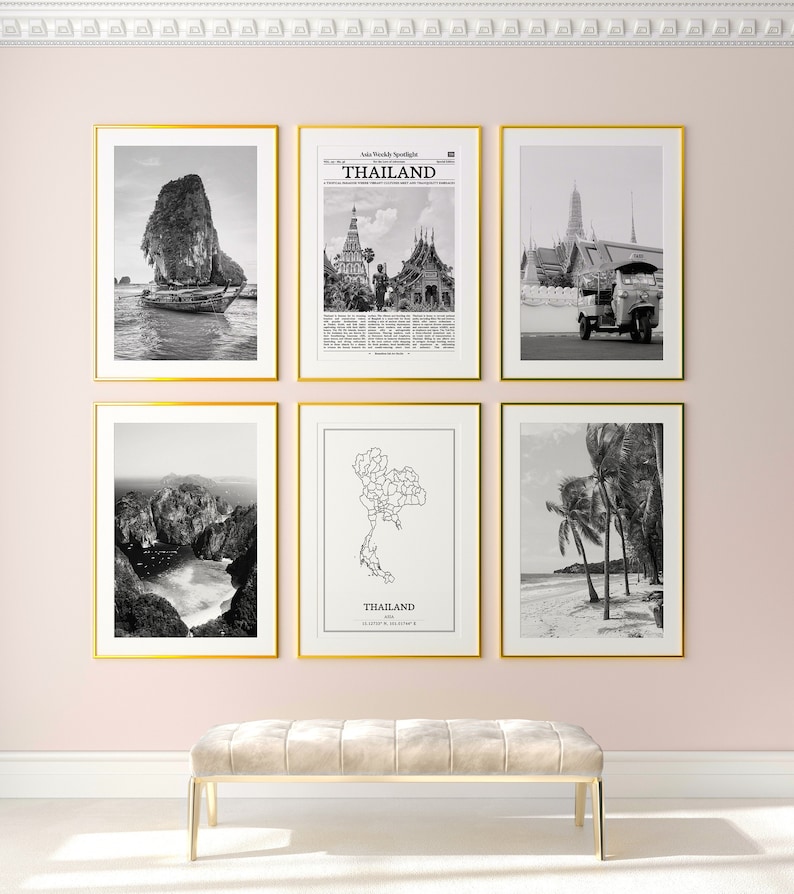 May include: A set of six framed black and white photographs of Thailand. The photos include a boat in a bay, a newspaper clipping about Thailand, a temple, a mountain range, a map of Thailand, and palm trees on a beach.