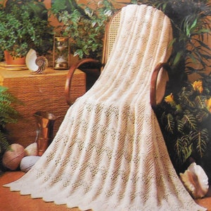 May include: A white crocheted throw blanket draped over a wicker chair. The blanket has a delicate, lacy pattern and is perfect for adding a touch of elegance to any room.