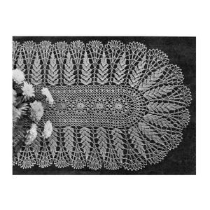 May include: A detailed, oval-shaped, white lace doily with a floral design. The doily features a central pattern of interconnected circles and is surrounded by a border of stylized leaves. The image is in black and white.
