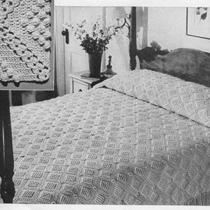 May include: A white crocheted bedspread with a diamond pattern and fringe. The bedspread is on a bed with a white headboard and a white pillow.