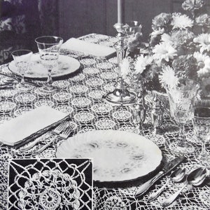 May include: Black and white photo of a crocheted table cloth with a floral design. The table is set with plates, silverware, and glasses. A candle is in the center of the table.