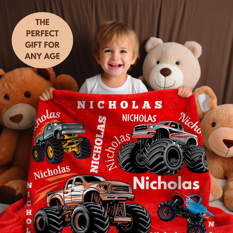 May include: A red blanket featuring monster truck graphics and the name "Nicholas" in white. The blanket has four different monster truck designs. The text "THE PERFECT GIFT FOR ANY AGE" is in a circle in the upper left corner.