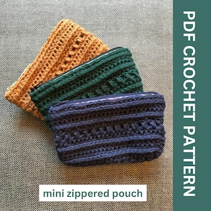 May include: Three crocheted mini zippered pouches in shades of orange, green, and navy blue. The pouches have a textured stitch pattern and a zipper closure. The image also includes the text "PDF CROCHET PATTERN" and "mini zippered pouch."