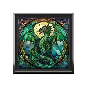 May include: A stained glass artwork depicting a green dragon with wings spread wide, set against a background of clouds and a circular frame.