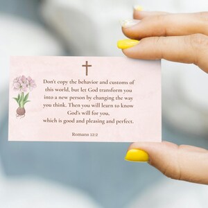 Può includere: Una carta rosa chiaro con una croce e testo da Romani 12:2. La carta presenta un'illustrazione floreale. Il testo recita: "Non conformatevi a questo mondo, ma siate trasformati..."