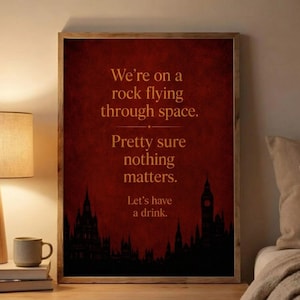 May include: A rectangular wall art print with a dark red textured background featuring the text: We're on a rock flying through space. Pretty sure nothing matters. Let's have a drink. The bottom shows a black silhouette of a city skyline.
