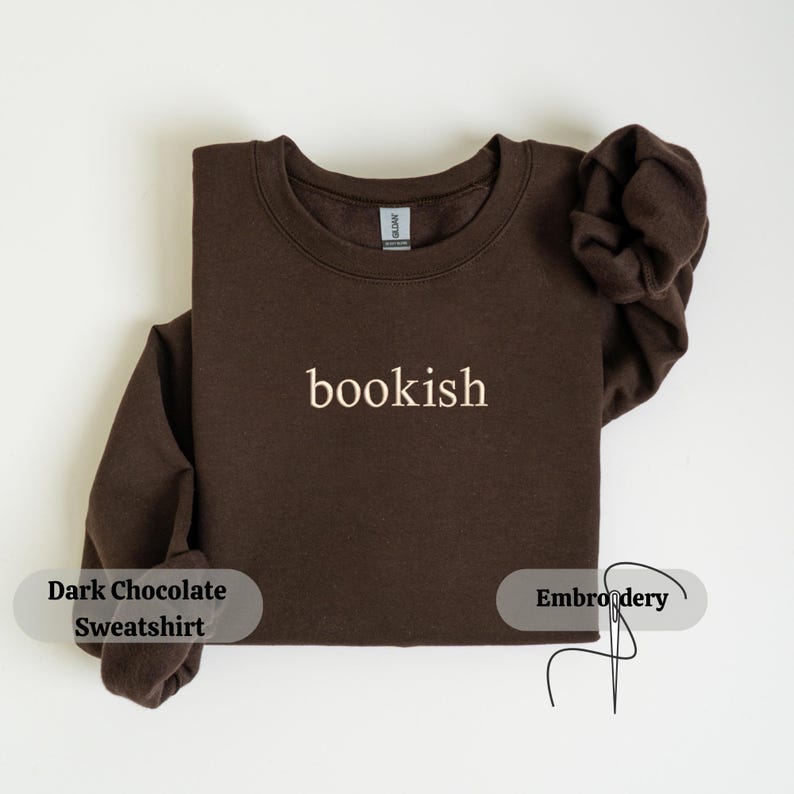K&ouml;nnte beinhalten: Ein dunkelbraunes Sweatshirt mit dem Wort "bookish" in einem helleren Farbton gestickt. Das Sweatshirt hat einen Rundhalsausschnitt, mit gefalteten &Auml;rmeln. Das Bild enth&auml;lt auch den Text "Dark Chocolate Sweatshirt" und "Embroidery".