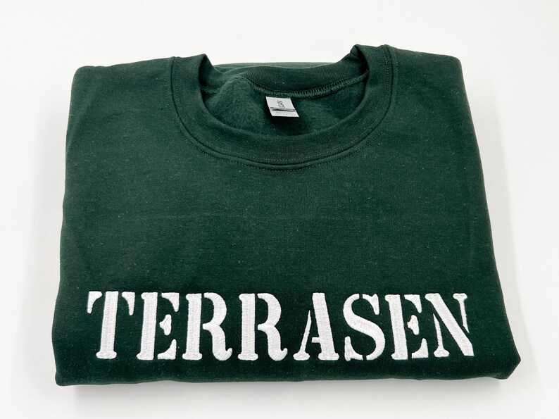 May include: A dark green sweatshirt with the word "TERRASEN" printed in white on the front.