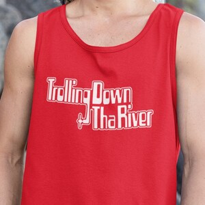 May include: A red tank top with a white graphic that says "Trolling Down Tha River". The person wearing the tank top is smiling and standing in front of a rocky background.