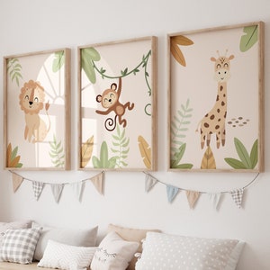Puede incluir: Tres ilustraciones enmarcadas de animales de la selva, un león, un mono y una jirafa, con follaje verde y un fondo beige claro. Los marcos son de madera clara y las ilustraciones son de estilo de dibujos animados. Los marcos están colgados en una pared blanca sobre un banco de madera con contenedores de almacenamiento.