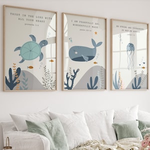 Peut inclure: Trois impressions encadrées avec un design sur le thème de la mer. Les impressions représentent une tortue, une baleine et une méduse. Chaque impression comprend un verset biblique. Les impressions sont dans un salon avec un canapé blanc, une table basse en bois et un vase de fleurs roses.