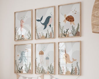 May include: A set of six framed prints featuring colourful illustrations of sea creatures, including a seahorse, whale, turtle, octopus, jellyfish, and narwhal. The prints are arranged in a grid pattern on a white wall above a wooden shelf with storage bins.