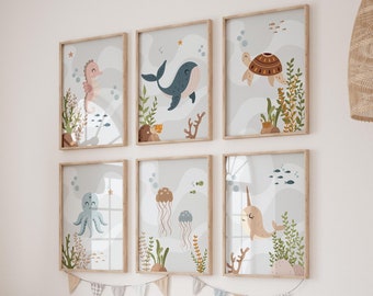 May include: A set of six framed prints featuring colourful illustrations of sea creatures, including a seahorse, whale, turtle, octopus, jellyfish, and narwhal. The prints are displayed on a white wall above a wooden shelf with storage bins and cushions.