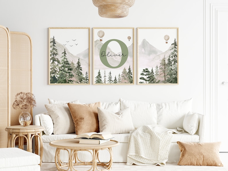 May include: Three watercolour prints featuring a mountain landscape with green trees, a light pink sky, and hot air balloons. The middle print features the letter "O" in green with the name "Oliver" written below it.