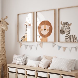 May include: Three framed illustrations of animals in a nursery setting. The illustrations feature a giraffe, a lion, and a zebra. The frames are light wood and the illustrations are in a cartoon style.