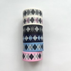 May include: A stack of six washi tapes with a black and white argyle pattern. The tapes are in various shades of blue and pink.