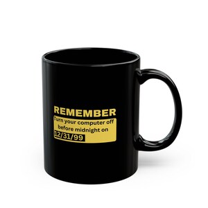 May include: Black ceramic coffee mug with a curved handle. The mug features the text "REMEMBER Turn your computer off before midnight on 12/31/99" in gold lettering on a yellow rectangle.