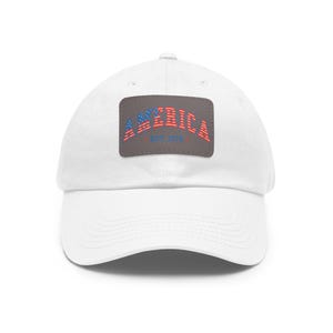 Könnte beinhalten: Weiße Baseballkappe mit gebogenem Schirm. Die Kappe hat einen rechteckigen Aufnäher mit dem Wort "AMERICA" in Rot und Blau sowie dem Text "EST 1776". Ein klassisches, lässiges Accessoire.