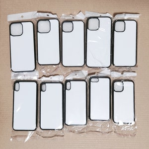 May include: Ten blank black phone cases with a cutout for the camera lens. The cases are arranged in two rows of five, and are all facing the camera.