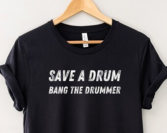 Puede incluir: Camiseta negra con texto blanco que dice "Save a Drum Bang the Drummer".