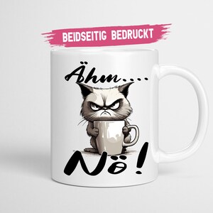 Könnte beinhalten: Weiße Keramiktasse mit einem Cartoon eines mürrischen Katers, der eine Kaffeetasse hält, und dem Text "Ähm... Nö!" darauf gedruckt. Die Tasse ist beidseitig bedruckt.