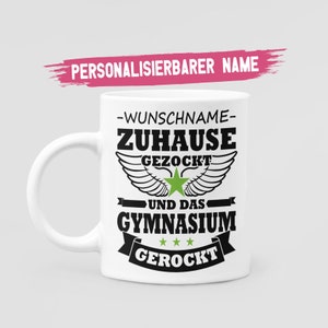 Könnte beinhalten: Weiße Keramiktasse mit schwarzem Text, der "Wunschname - Zuhause Gezockt - Und das Gymnasium Gerockt" mit einem grünen Stern und Flügeln lautet.