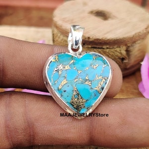May include: A silver heart-shaped pendant with a turquoise and gold inlay. The pendant is approximately 2.5 inches in length.