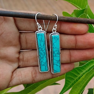 Puede incluir: Un par de pendientes de plata con inserciones rectangulares de turquesa.