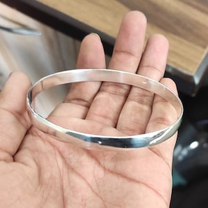 May include: A silver bangle bracelet with a smooth, polished finish.