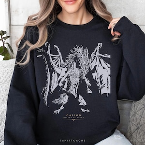 May include: Black sweatshirt featuring a detailed gray graphic of a skeletal dragon with outstretched wings. The text "CALIGO Miasma of Night" is below the graphic. The brand name "TSHIRTCACHE" is at the bottom.