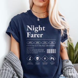 May include: A navy blue short-sleeve t-shirt featuring white text and graphics. The design includes the words Night Farer, a percentage breakdown of player traits, a barcode, and four diamond icons with labels like Requires More Flasks.