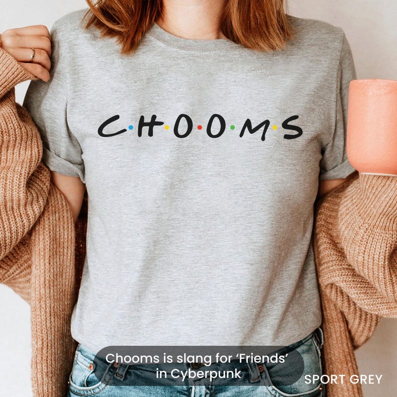 May include: Sport grey t-shirt with the word "CHOOMS" in a font style similar to the TV show "Friends". The letters are in black with the "O"s in yellow and red. The shirt also has the text "Chooms is slang for 'Friends' in Cyberpunk".