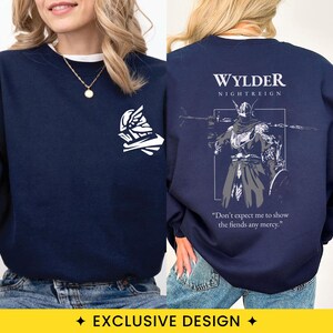 May include: A navy blue crewneck sweatshirt featuring a white graphic of a helmet on the front left chest. The back displays a white illustration of a knight with the text WYLDER NIGHTREIGN and the quote Don't expect me to show the fiends any mercy.