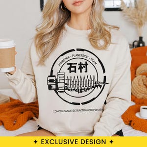 May include: A beige crewneck sweatshirt featuring a black graphic print of a circular emblem with the text Ishimura Planet-Side Team, Japanese characters, and the text Concordance Extraction Corporation surrounding a stylized mechanical ship.
