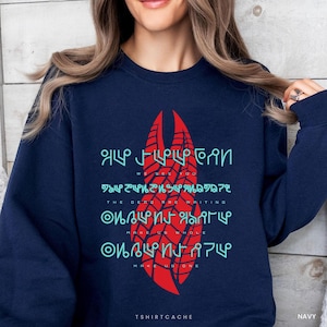 May include: A navy blue crewneck sweatshirt featuring a large red graphic of a double-helix structure. The design includes light blue alien-style symbols and English text that reads: WE SEE YOU, THE DEAD ARE WRITING, MAKE US WHOLE, MAKE US ONE.