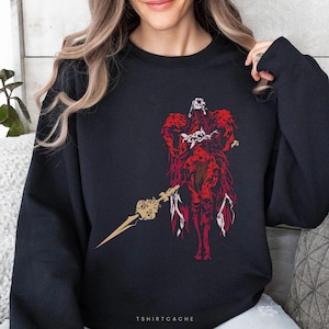 May include: Black sweatshirt featuring a red and gold graphic of a warrior holding a spear. The graphic has intricate details and a stylized design. The text "TSHIRTCACHE" is printed at the bottom.
