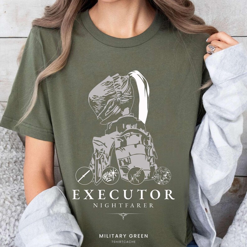 May include: Military green t-shirt with a gray graphic of a figure in armor, with the words "EXECUTOR NIGHTFARER" in white. Below the text is the phrase "MILITARY GREEN TSHIRTCACHE". The design includes circular emblems.