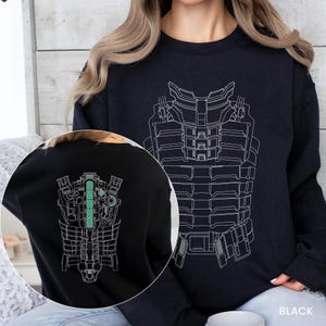 May include: Black sweatshirt featuring a white line drawing of a futuristic armored suit on the front and back. The back design includes a vertical green stripe. The word "BLACK" is visible in the lower right corner.