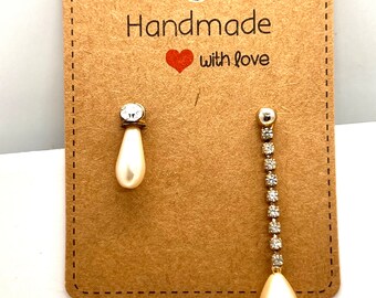 May include: A pair of handmade earrings with a pearl drop and a crystal chain. The earrings are displayed on a brown card with the text "Handmade with love".