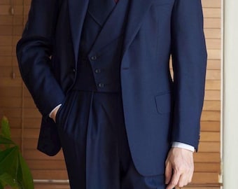 May include: A navy blue suit with a double-breasted jacket and a vest. The suit has a white shirt with a red and white striped tie.