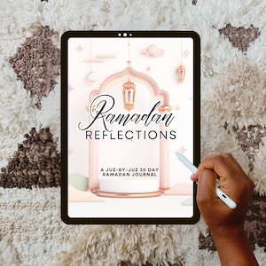 May include: A digital tablet displaying a pink and gold Ramadan Reflections journal cover with the text "Ramadan Reflections" and "A Juz-By-Juz 30 Day Ramadan Journal".